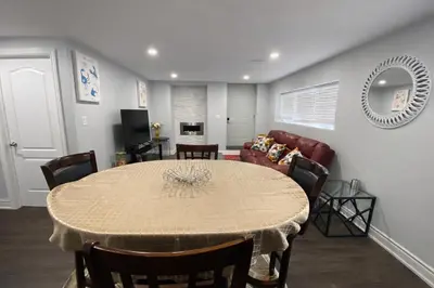 a dining room with a table and a living room at Cozy 3BR Caledon Basement Suite with Private Access, Full Kitchen, WiFi, Laundry, Backyard Basketball Court & Creek Trail, 5 Mins to Brampton! Great for Families & Long Stays! in Caledon