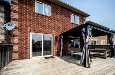 a wooden deck with a pavilion in front of a brick building at Private Room In Luxury Home in Innisfil