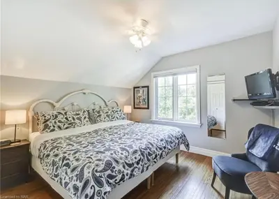 a bedroom with a bed and a tv and a window at Matisse B&B in Niagara on the Lake