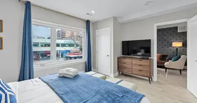 a bedroom with a large bed and a television at Casa Hotel Contemporary 2BR Suite w Patio & BBQ in Toronto