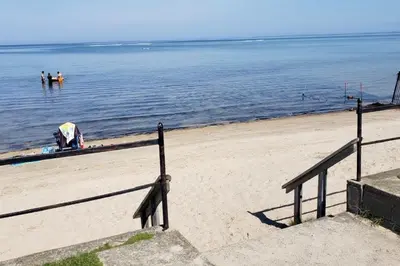 a beach with people standing in the water at The Driftwood Deck 5A in Wasaga Beach
