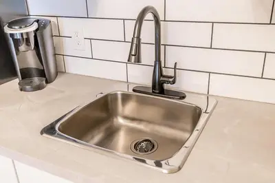 a stainless steel sink in a kitchen with white tiles at The Landing Pad - Condo in Collingwood in Collingwood