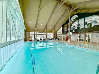 a large swimming pool with blue water in a building at King Suite heated Pool Sauna and Kitchen in Shanty Bay