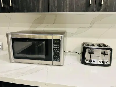 a microwave sitting on a counter next to a toaster oven at World Cup Soccer Fans Stay! Luxury 4BR Family Retreat in Thorold, Just 10 Mins Niagara Falls, Clifton Hill & Wineries Free Wi-Fi, Free Parking in Thorold