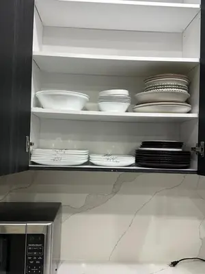 a kitchen cabinet with plates and dishes on a shelf at World Cup Soccer Fans Stay! Luxury 4BR Family Retreat in Thorold, Just 10 Mins Niagara Falls, Clifton Hill & Wineries Free Wi-Fi, Free Parking in Thorold