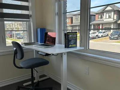 a desk with a laptop and a book and a chair at World Cup Soccer Fans Stay! Luxury 4BR Family Retreat in Thorold, Just 10 Mins Niagara Falls, Clifton Hill & Wineries Free Wi-Fi, Free Parking in Thorold