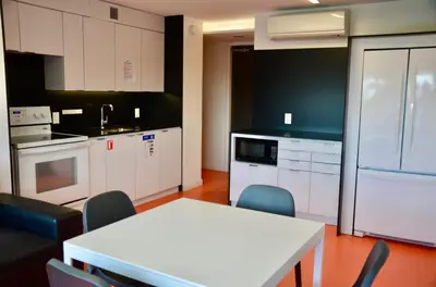 a kitchen with white cabinets and a table and chairs at Tartu College Student Residence in Toronto