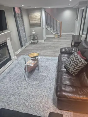 a living room with a leather couch and a fireplace at Two bedroom basement apartment in Whitby
