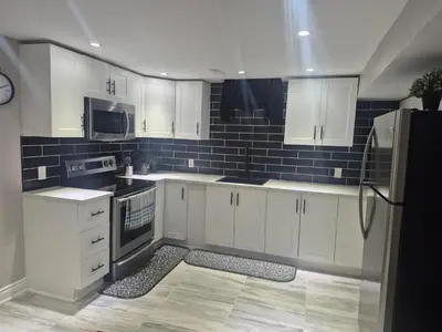 a kitchen with white cabinets and black appliances at Two bedroom basement apartment in Whitby
