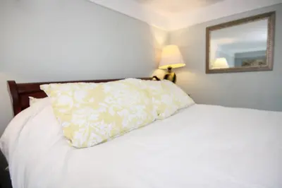 a white bed with a pillow and a mirror at The Jypsy Inn - The Royal Suite Bracebridge in Bracebridge
