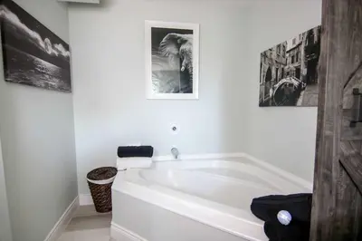a white bath tub in a bathroom with two pictures on the wall at The Jypsy Inn - Tuxedo Room Muskoka in Bracebridge