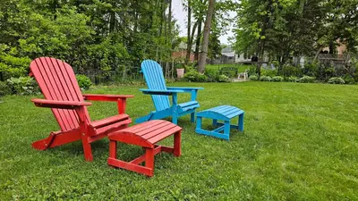 three colorful chairs sitting in the grass in a yard at Cozy 1BR Garden Suite Innisfil Beach Park in Innisfil