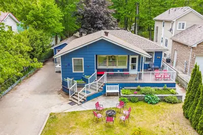a blue house with a table and chairs in the yard at Wavy Daze in Wasaga Beach