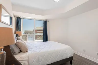 a bedroom with a bed and a large window at Stylish 2BR with Great View! Steps from Square One in Mississauga