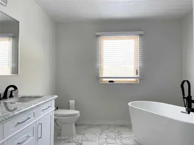 a white bathroom with a tub and a toilet at Four and half bedrooms 10 Acres of forest with trails in Tottenham