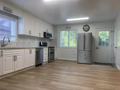 a kitchen with a refrigerator and a clock on the wall at Four and half bedrooms 10 Acres of forest with trails in Tottenham