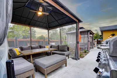 a patio with a table and couches and an umbrella at Adrian's Suites 1Bedroom Junior Suite in Wasaga Beach