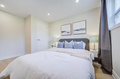 a white bedroom with a large bed with blue pillows at nest in orchard-main unit room in Toronto