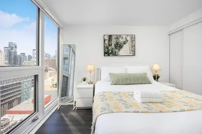 a white bedroom with a bed and a large window at 2br Luxury & Modern Suite 5 Minutes from Eaton Center in Toronto