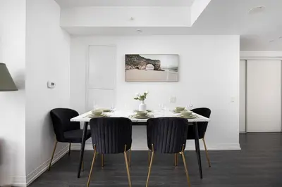 a dining room with a white table and chairs at 2br Luxury & Modern Suite 5 Minutes from Eaton Center in Toronto