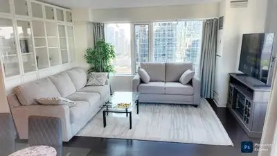 a living room with a couch and a chair and a tv at Pantages Skyline Suite in Toronto Centre - Free Parking in Toronto