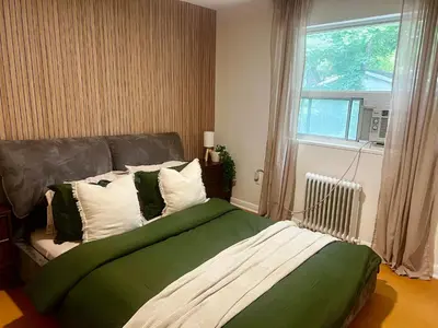 a bedroom with a green and white bed with a window at Cozy Upper Beaches Apartment in Toronto