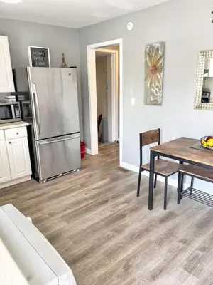 a kitchen with a table and a stainless steel refrigerator at Cozy Retreat with Netflix and Work Desk in Fort Erie