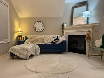 a living room with a blue couch and a clock at Luxurious Villa 3 Living Rooms, 1 sofa bed, 4 bedrooms, 4 Beds, 4 Toilets, 1 hour To Toronto in Oshawa