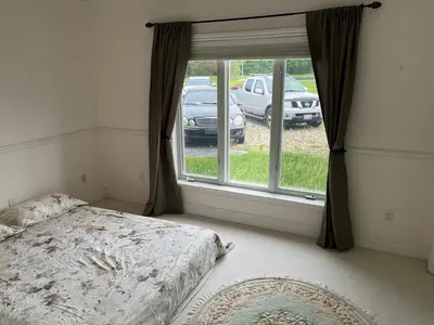 a bedroom with a bed and a window with a car outside at Summer Escape Close to the City in Newmarket