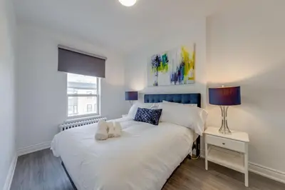 a bedroom with a white bed with two shoes on it at The Bloor Spadina Getaway With 3-Bedroom and Private Patio in Toronto