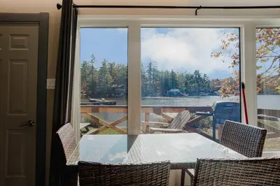 a table and chairs on a balcony with a view of a lake at 2-Bedroom Cottage #10 - Pitch Pine in Gravenhurst