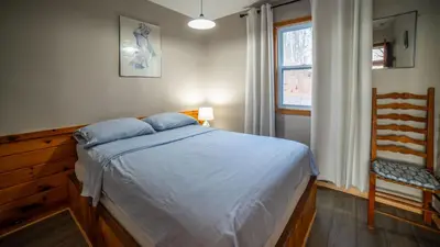 a bedroom with a bed and a chair and a window at Lake Muskoka 2-bedroom Cottage - Pier 100 #50 in Port Carling