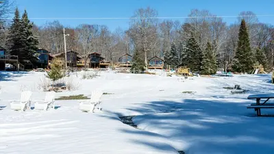 a snow covered yard with chairs and a picnic table at Lake Muskoka 3-bdrm Cottage - Pier 100 #70 in Port Carling