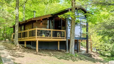 a log cabin in the woods with a balcony at Lake Muskoka Deluxe 3-bdrm Cottage - Pier 100 #80 in Port Carling