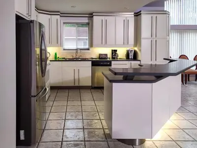 a kitchen with white cabinets and a black refrigerator at Muskoka Lakefront 4-bdrm Guest House in Port Carling
