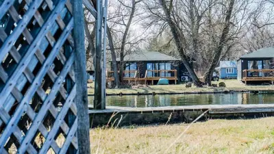 a view of a house from behind a fence at 2-bedroom Lake Front Cottage in Harwood ON #6 in Harwood