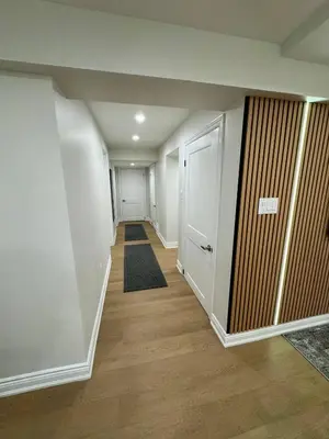 a hallway with white walls and wooden floors and a door at 2 BR Private Basement Suite | Minutes from YYZ in Brampton