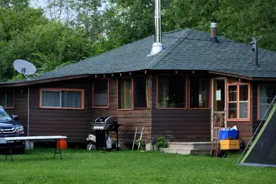 a brown house with a grill in the yard at Balsam Lake - 2-Bedroom Cottage #8 in Kawartha Lakes