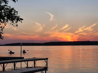 two people in the water at a dock at sunset at Balsam Lake - 2-Bedroom Cottage #8 in Kawartha Lakes