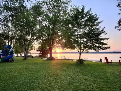 a park with trees and benches and the water at 2-Bedroom - Balsam Lake Cottages Resort #12 in Kawartha Lakes