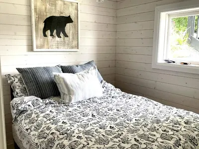 a bedroom with a bed with a black and white blanket at The Muskoka Nest in Utterson