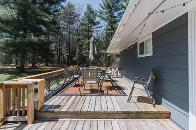 a wooden deck with chairs and an umbrella at Private cottage with 26 acre & outdoor games in Bracebridge