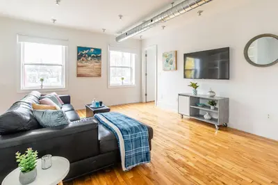 a living room with a black leather couch and a flat screen tv at Stylish & Pet-Friendly 2BR Suite in Trendy Leslieville with Portable AC Nearest Intersection Eastern Ave in Toronto