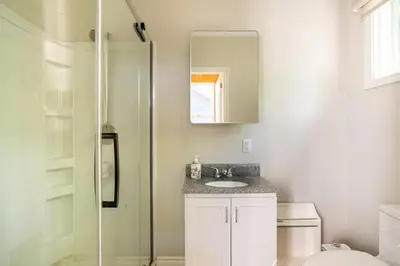 a bathroom with a toilet and a sink and a mirror at The Beach House - Steps to Beach Area 3 4BR in Wasaga Beach