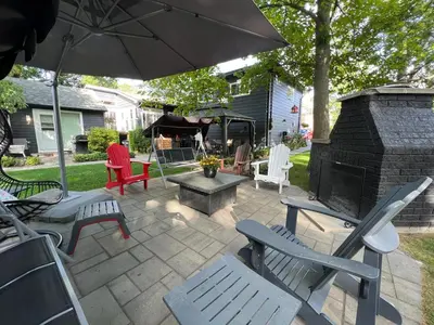 a patio with chairs and an umbrella and a fireplace at Spacious Second Floor Garden View Apartment in Wasaga Beach