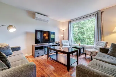 a living room with a couch and a table and a tv at Spacious Second Floor Garden View Apartment in Wasaga Beach