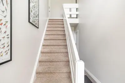 a staircase in a house with white walls and carpet at Spacious Second Floor Garden View Apartment in Wasaga Beach