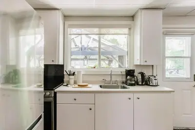 a white kitchen with a sink and a window at The Cozy Shore Cottage - Large in Wasaga Beach