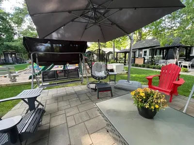 a patio with two chairs and an umbrella at The Cozy Shore Cottage - Large in Wasaga Beach