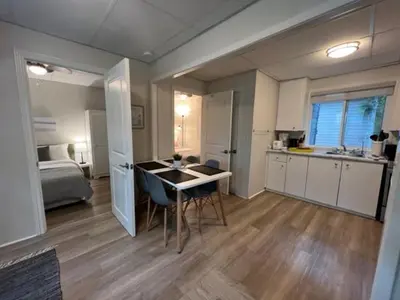 a room with a kitchen and a table and a bed at The Cozy Shore Cottage - Standard Attached in Wasaga Beach